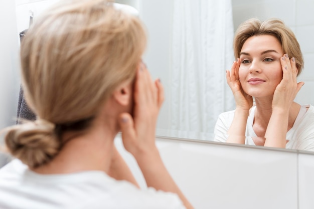 Woman looking in the mirror and smiles | Free Photo