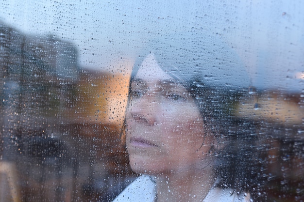 雨の日に窓の外を見ている女性 プレミアム写真