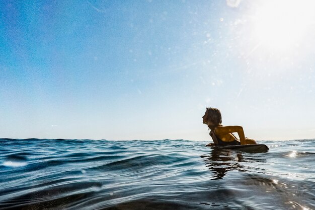 Free Photo | Woman lying on surfboard in water