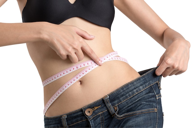 ジーンズで失った体重を示す腰を測定する女性 Premium写真