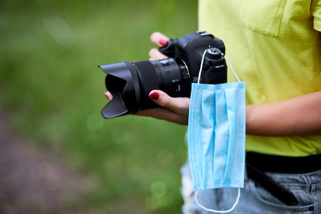 防護マスクと屋外の手で写真のカメラを持つ女性のカメラマン プレミアム写真