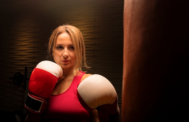 Free Photo Woman In Pink With Boxing Gloves Training With Punching Bag