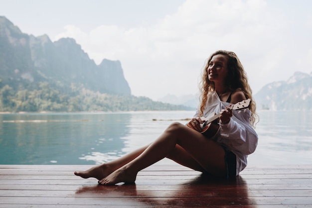 Premium Photo | Woman playing ukulele by the water