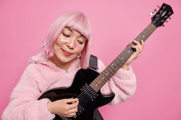 女性のポップバンド歌手がアコースティックエレキギターを弾き ファッショナブルな服を着ています 無料の写真