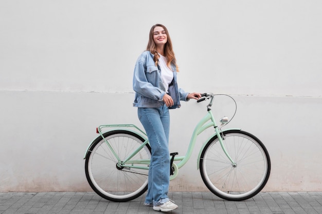 街の屋外で自転車を持ってポーズをとる女性 無料の写真