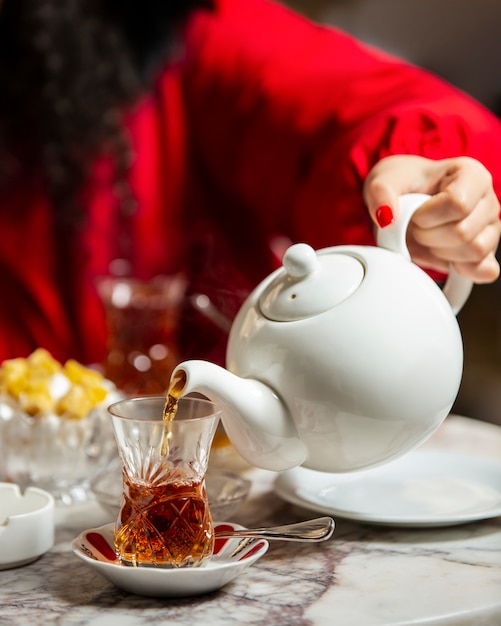 ティーポットから紅茶をアルムドゥグラスに注ぐ女性 無料の写真