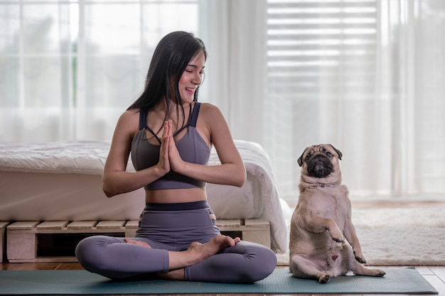 Woman practice yoga with dog pug breed Premium Photo
