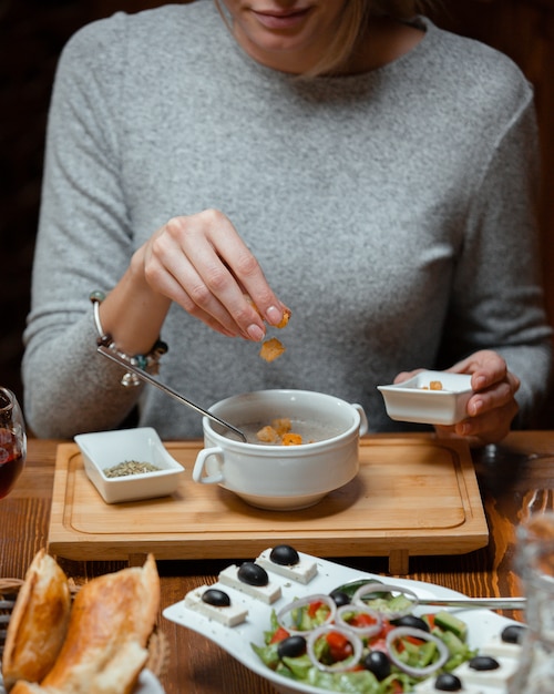 Woman putting bread stuffing cubes in her mushroom soup ...