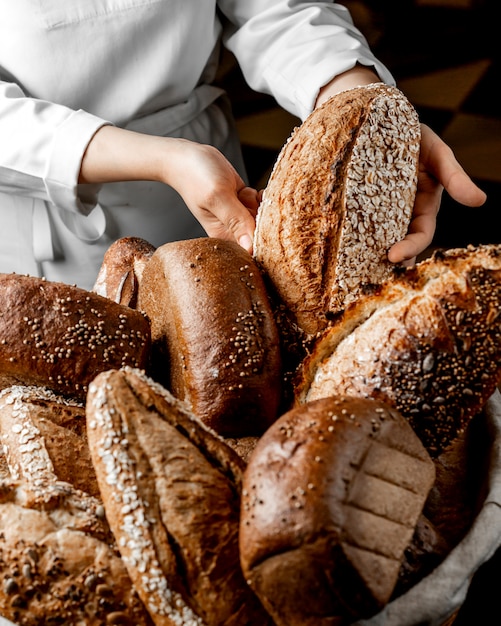 Free Photo | Woman putting whole grain bread bun among other breads