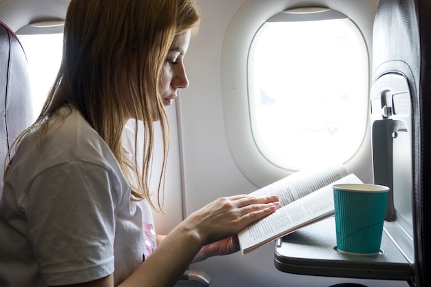 Free Photo | Woman reading a book in a plane