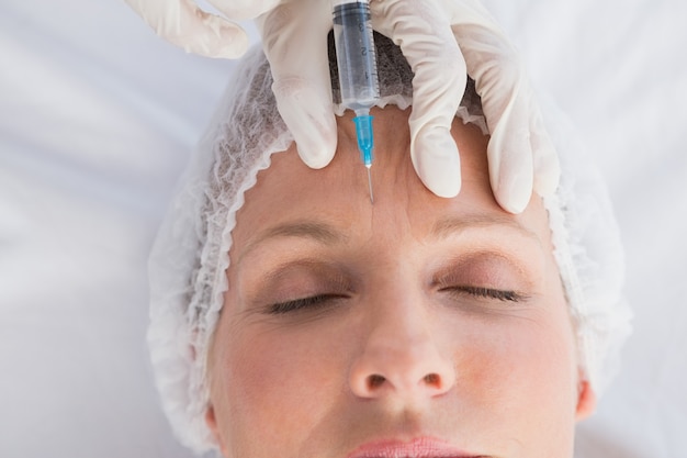 Woman receiving botox injection on her forehead Premium Photo