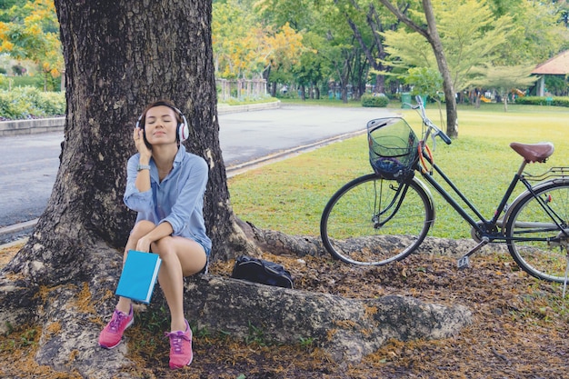 Woman relax time in park. she listening music and read book under ...