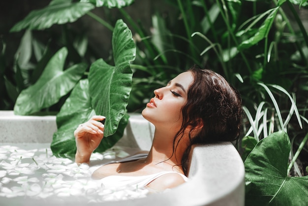 Woman relaxing in round outdoor bath with tropical flowers. Premium Photo