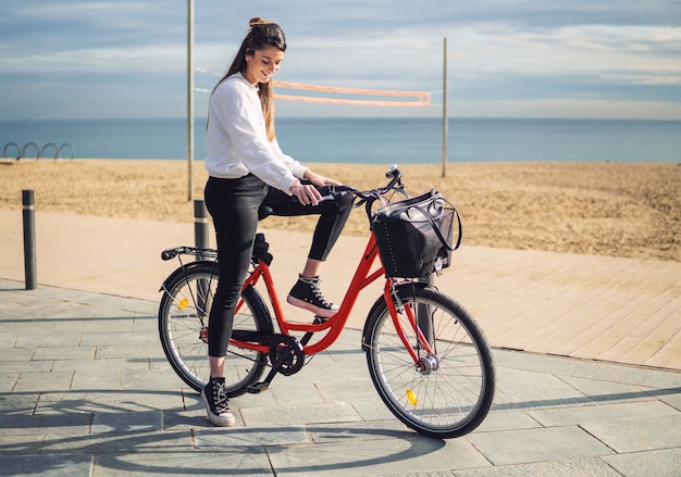 夏の砂浜に沿って自転車に乗る女性。健康とスポーツのコンセプト プレミアム写真