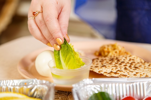 Premium Photo A Woman S Hand Dips A Leaf Of Lettuce In Salt Water During The Pesach Seder