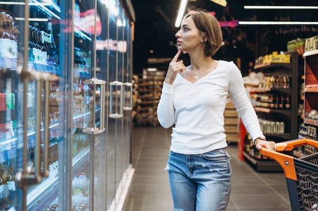 Woman shopping at the grocery store, by the refrigerator Free Photo