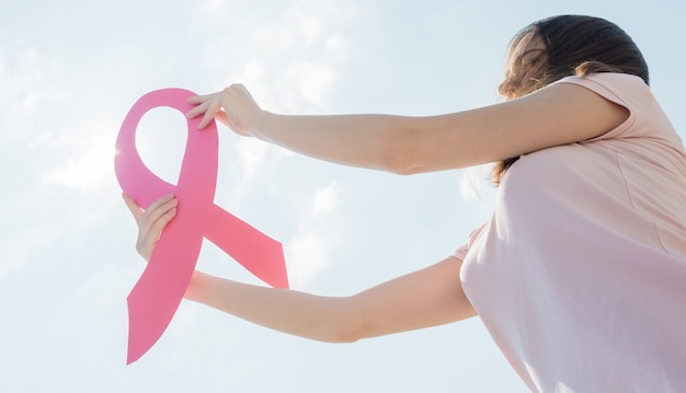 Woman showing pink ribbon to support breast cancer. Premium Photo