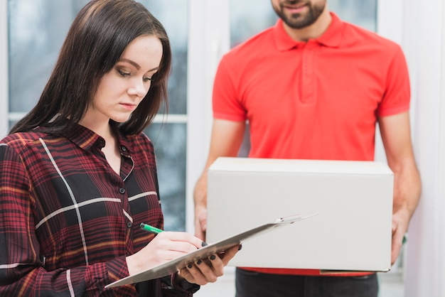 Woman signing receipt near crop courier Free Photo