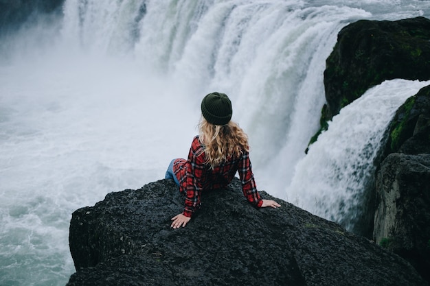Free Photo | Woman sit on edge of cliff on waterfall
