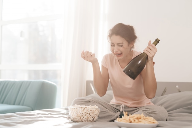 Woman Sits On Bed In Bright Room With Bottle Of Champagne Premium Photo