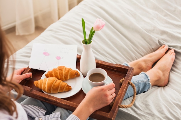 Woman sitting on bed with coffee on tray Free Photo