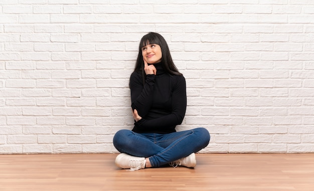 Woman Sitting On The Floor Thinking An Idea While Looking Up