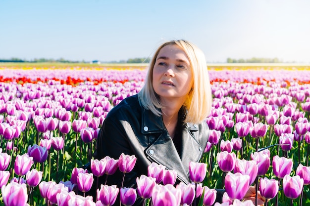 オランダ アムステルダム地方の色とりどりのチューリップの花畑に座っている女性 オランダのチューリップ畑と魔法のオランダの風景 プレミアム写真