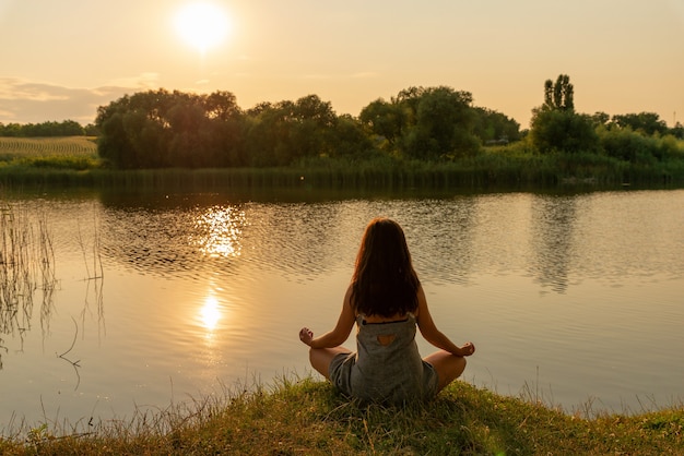 Premium Photo | Woman sitting in lotus position in meditation on a hill ...