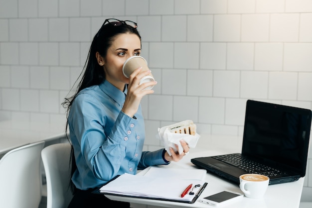 Premium Photo | Woman sitting in the office at the table drinking coffee