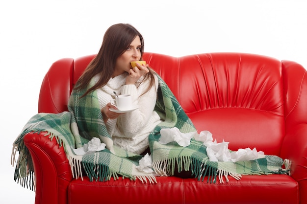 Woman sitting on the couch with a lemon in the mouth Free Photo