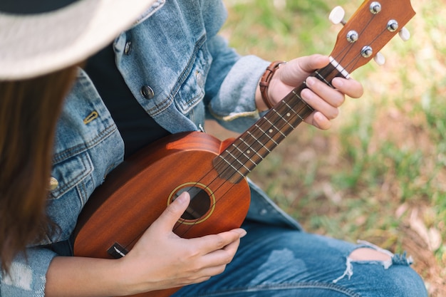 Premium Photo | A woman sitting and playing ukulele in the outdoors