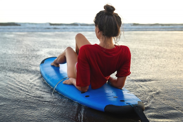Premium Photo Woman Sitting On Surfboard On The Beach After Her Surfing Session