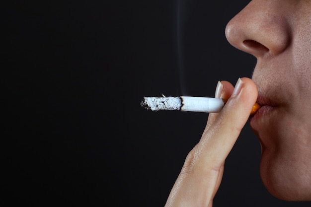 Premium Photo | Woman smokes a cigarette on dark