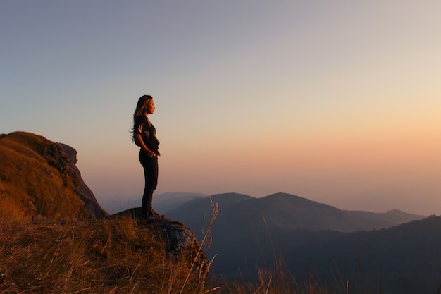 Download this Woman standing on a mountain looking at sunset Free Photo