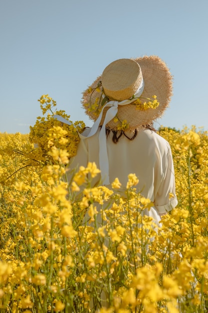 Premium Photo | Woman standing in rapeseed field rear view from behind ...