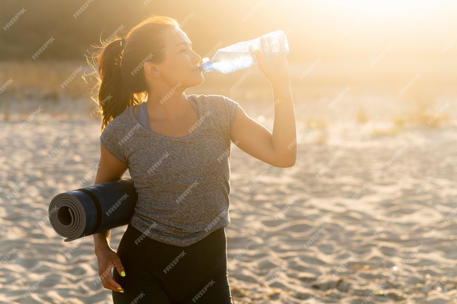 Free Photo | Woman staying hydrated while exercising on the beach