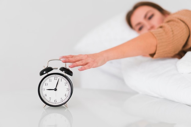 Woman stopping the alarm clock Free Photo