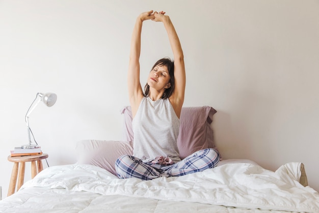 Woman stretching arms on bed in the morning Free Photo