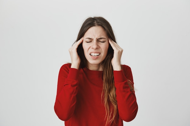 片頭痛に苦しんでいる女性 こめかみをこすり 目を閉じて顔をしかめ 頭痛を感じる 無料の写真