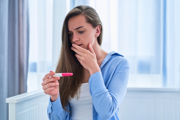 Premium Photo | Woman surprised by positive pregnancy test result ...