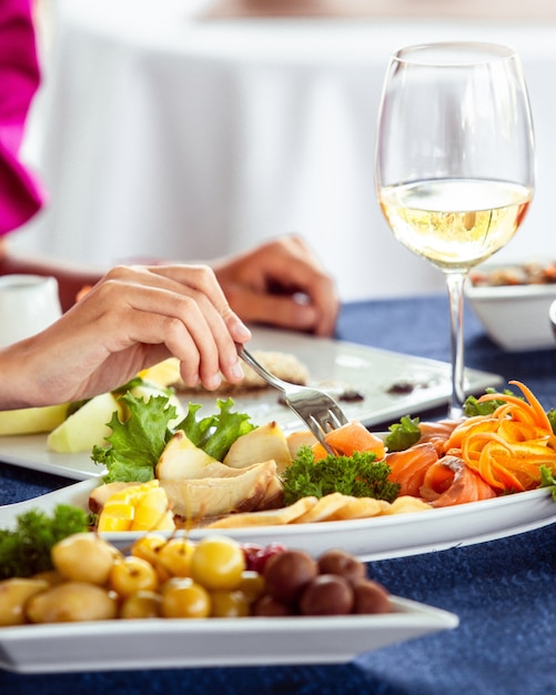 Woman taking smoked salmon from platter Free Photo