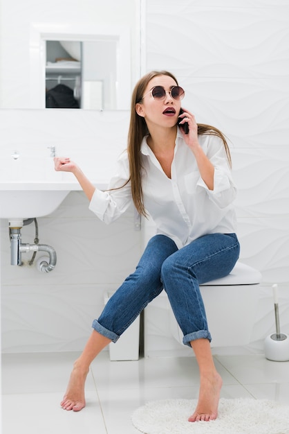 Free Photo Woman Talking On Phone While Sitting On The Toilet