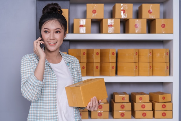 Woman talking with her smartphone at home office, small online business owner Premium Photo