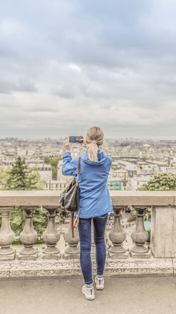 曇りの天候で都市の写真を撮る女性観光客 プレミアム写真