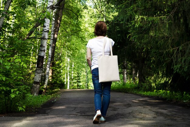 Download Premium Photo | Woman walking in the park carrying empty ...