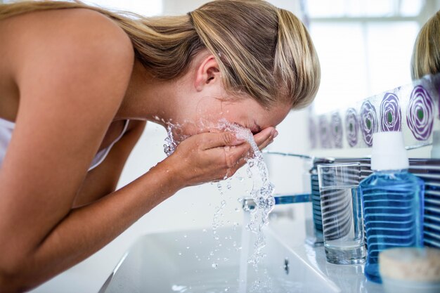 Premium Photo Woman Washing Her Face In The Bathroom