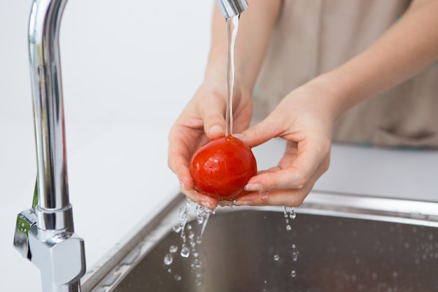 Woman washing tomato with tap water Photo | Free Download