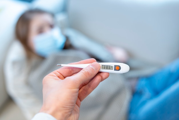Woman wearing surgical face mask and thermometer Free Photo