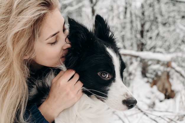 雪の中で黒と白のボーダーコリー犬と女性 プレミアム写真