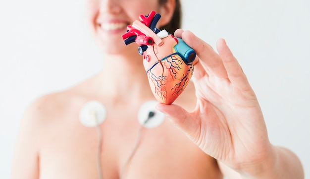 Woman with electrodes holdingÂ figurine of heart Free Photo